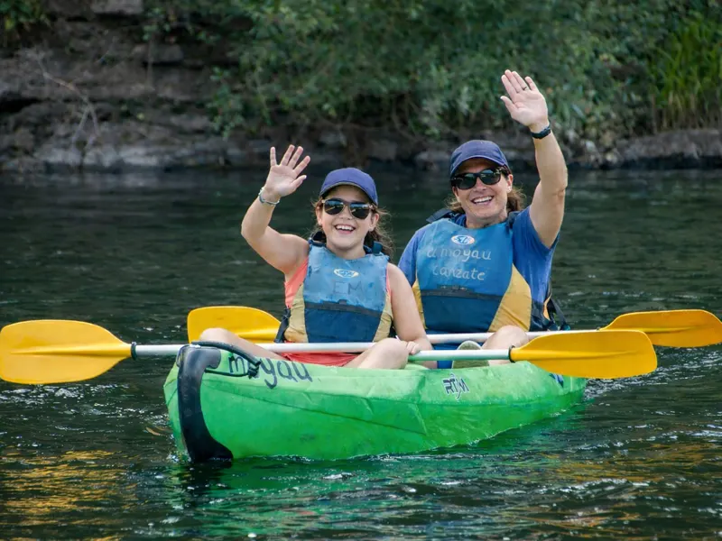 Madre e hija en una canoa saludando con la mano mientras hacen la bajada del Sella