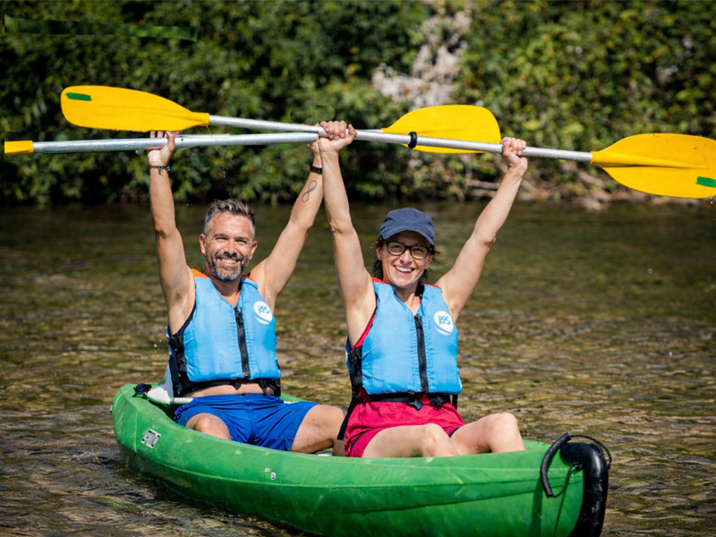 Pareja en canoa con los remos en alto haciendo el descenso del Sella en canoa